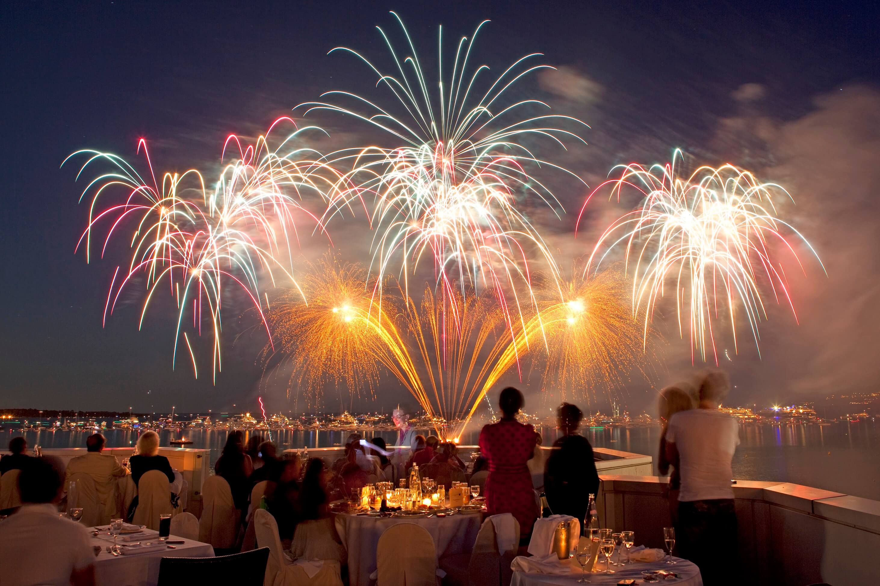 Des personne regardant un feu d'artifice depuis un restaurant