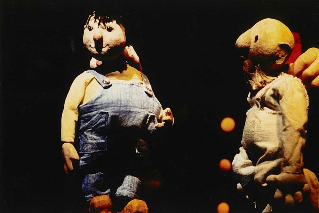 Photographie de deux marionnettes manipulées par un.e marionnettiste durant le spectacle « Temps de chien ou Noé l’endormi » : l’une représentant Coluche (à gauche) et l’autre Noé (à droite).